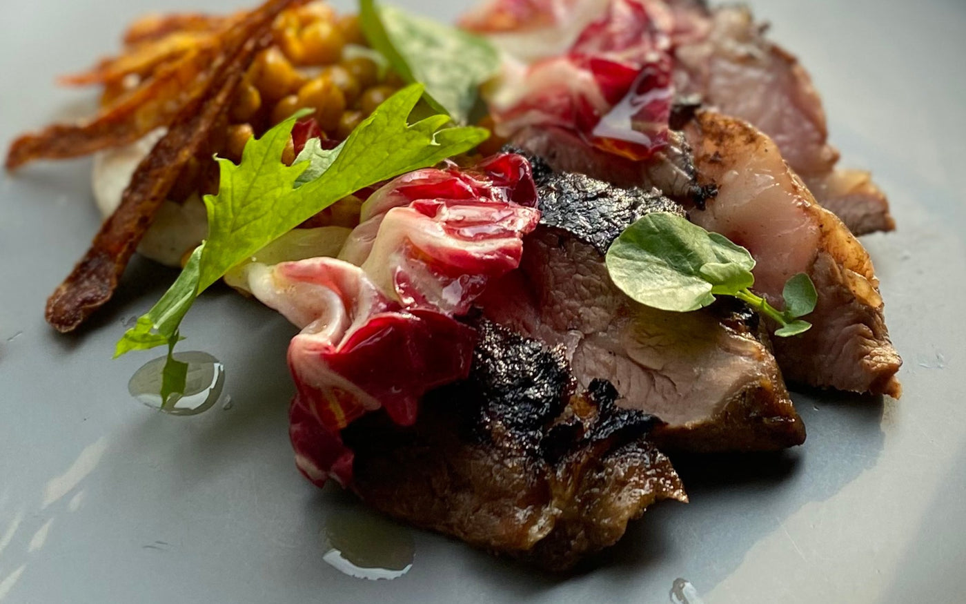 Seared lamb rump with roasted spring vegetables, pomegranate and red wine jus