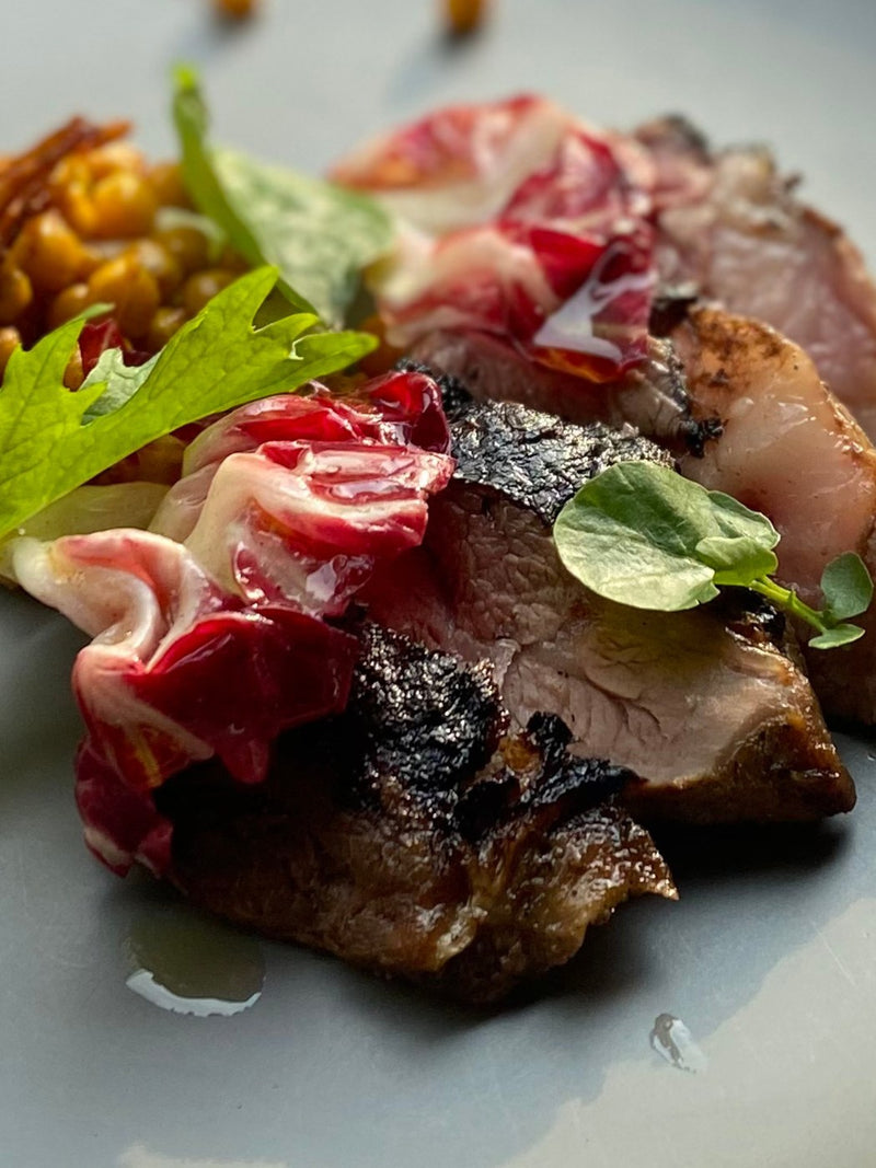 Seared lamb rump with roasted spring vegetables, pomegranate and red wine jus