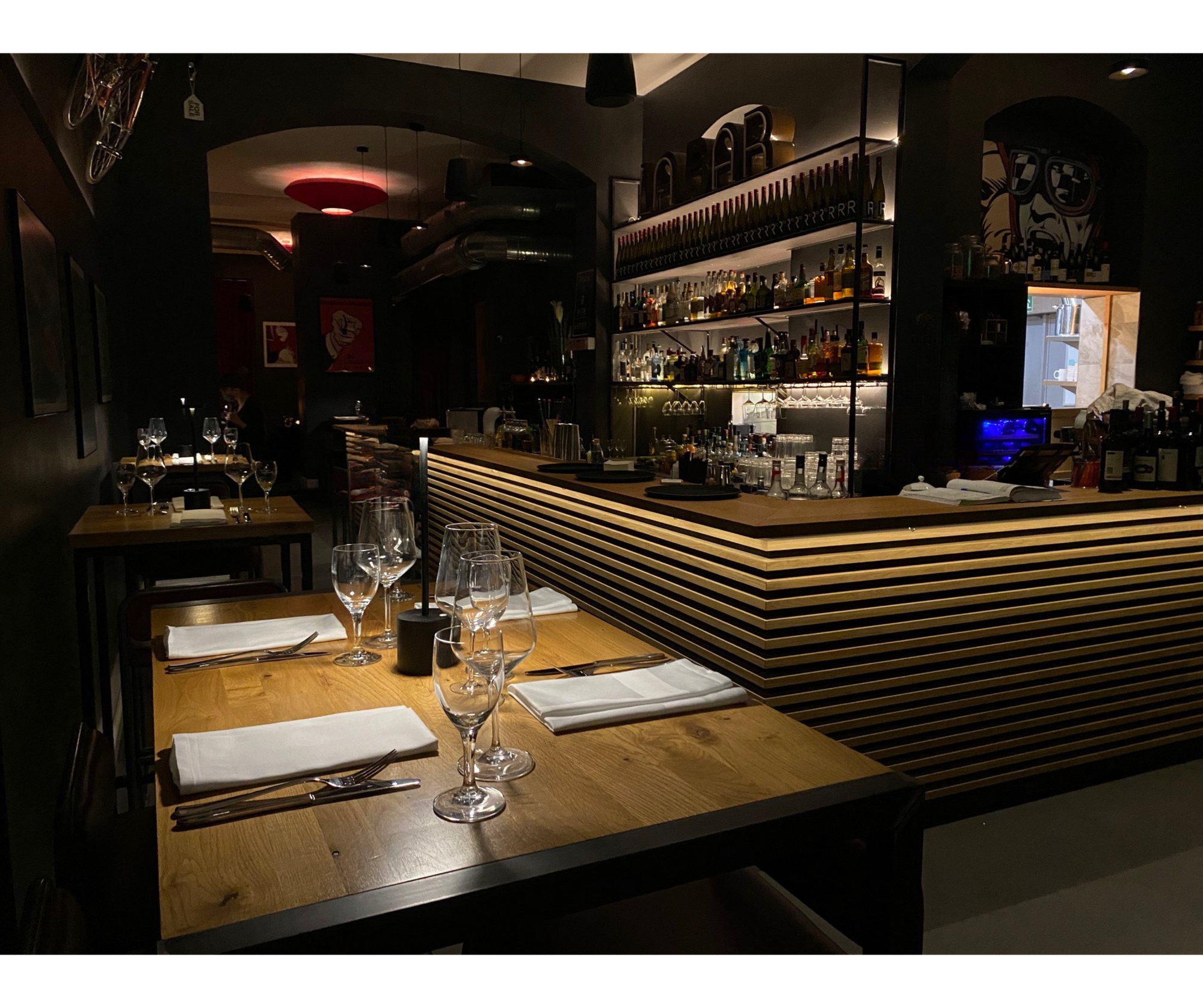 Der Gastraum im R10 am Abend: eingedeckte Tische vor der Bar mit beleuchteten Flaschenregalen
