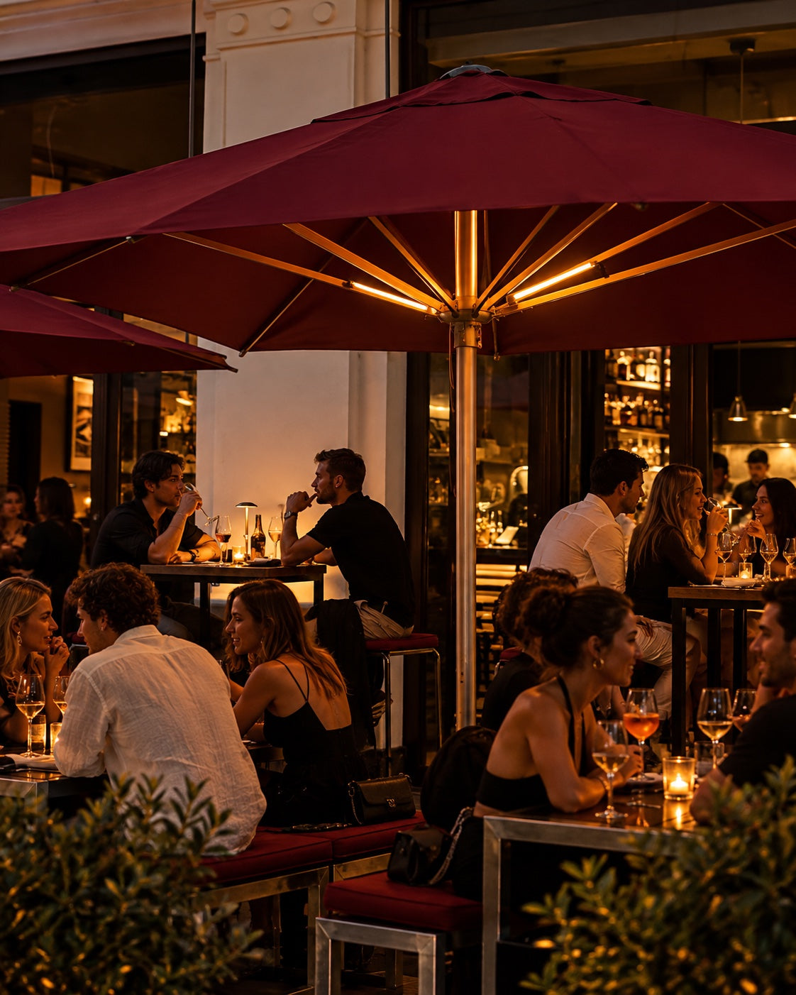 Guests with drinks under the umbrellas on the R10 terrace at dusk